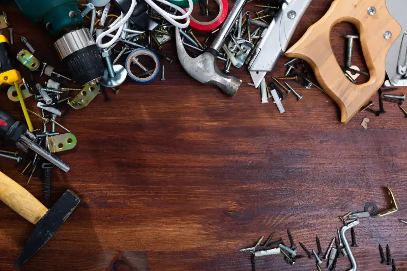 Hand tools, nails, and screws on a wooden table