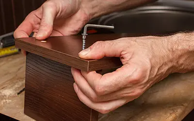 A pair of hands assembling a piece of furniture.