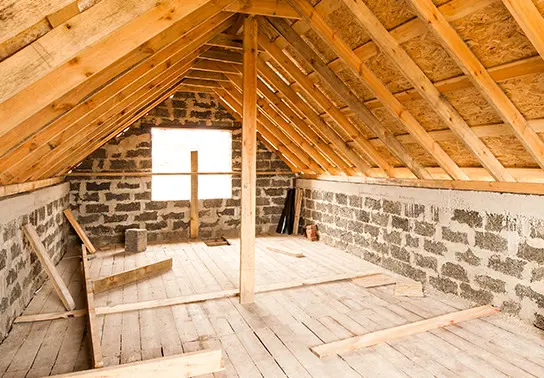 An unfinished attic with exposed brick and wood.