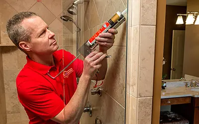 A My Handyman technician caulking a shower.