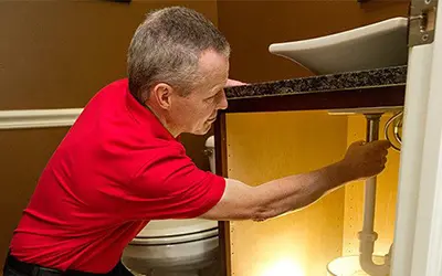 A My Handyman technician repairing some plumbing under a sink.